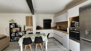 Une cuisine moderne équipée d’une table à manger, de chaises, d’un réfrigérateur et d’un four à micro-ondes.