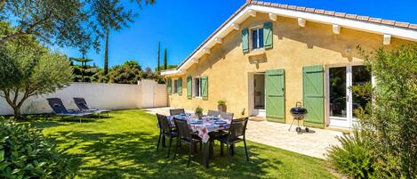 A house with a patio, a table with chairs, and a barbecue grill.