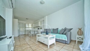 A spacious living area with a sofa, coffee table, and a dining table with chairs. - Armonia Apartment in Kouverta (Ermioni)