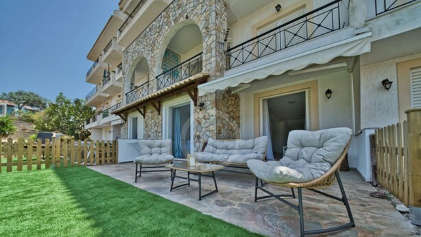 A two-story building with stone facade, a balcony, and a well-maintained lawn. - Armonia Apartment in Kouverta (Ermioni)