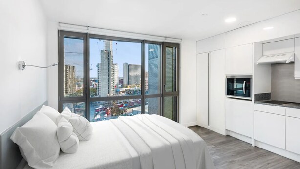 Ein modernes Schlafzimmer mit großem Fenster, einem Bett und einer Küchenzeile.