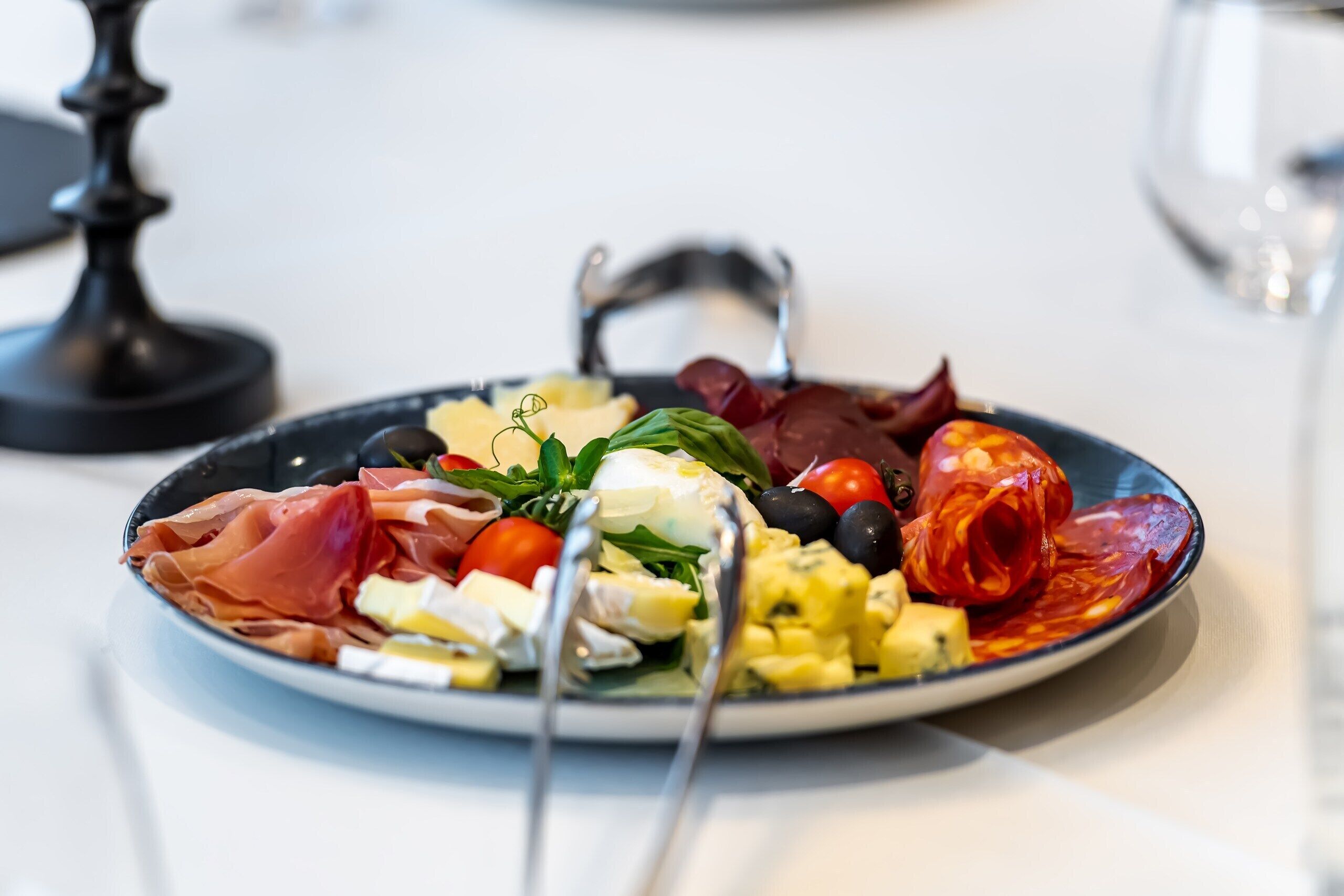 A plate of food with various items including tomatoes, olives, and a red pepper.