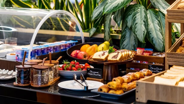 Un bufé con diversos alimentos, incluyendo frutas, pasteles y un cartel que anuncia un pastel por la paz mundial.