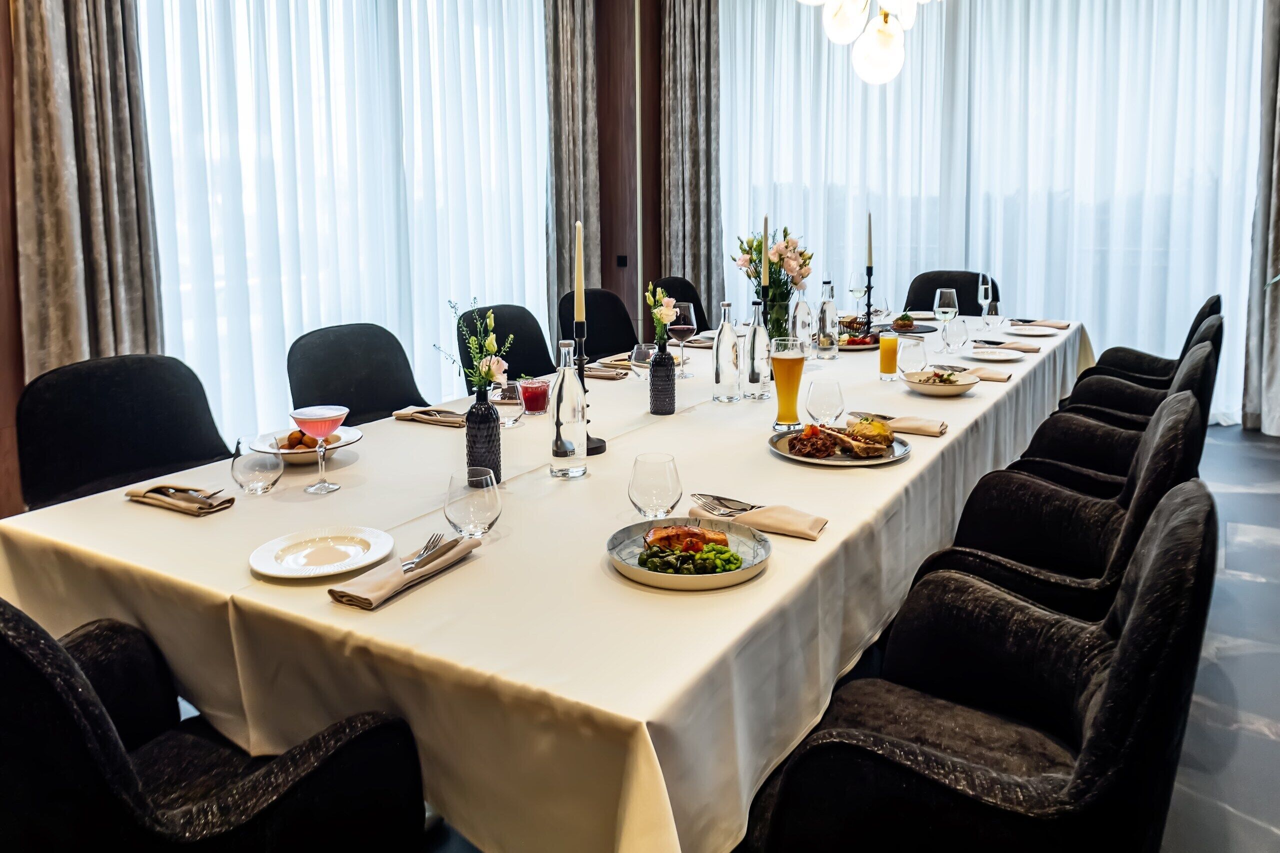 A dining table set with plates, cutlery, glasses, and a vase of flowers.