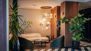 Un lobby moderno con un sofá, sillas, una mesa de centro y una lámpara decorativa.