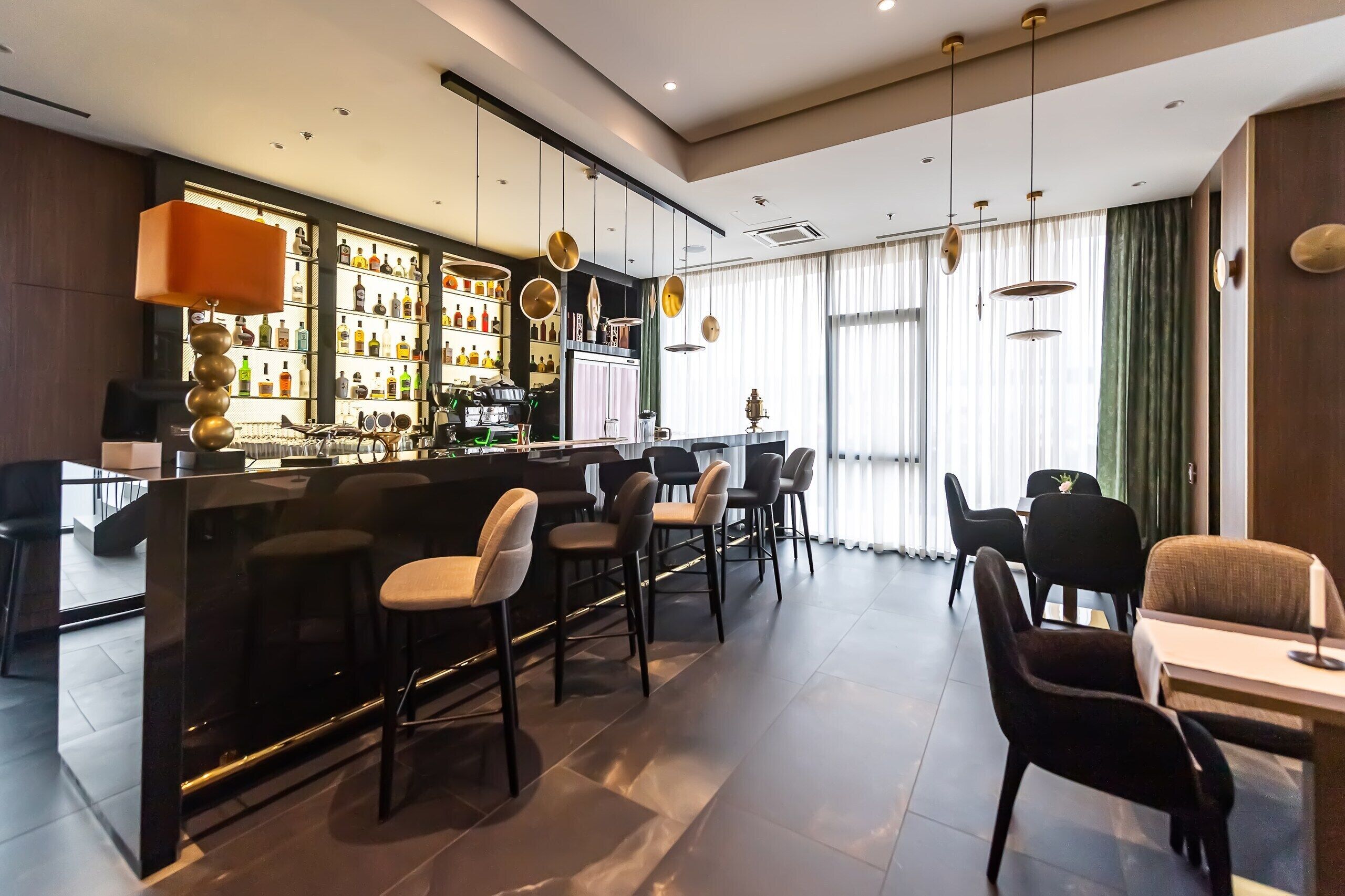 A bar area with stools, a counter, and a variety of bottles.