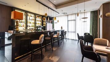 A bar area with stools, a counter, and a variety of bottles.