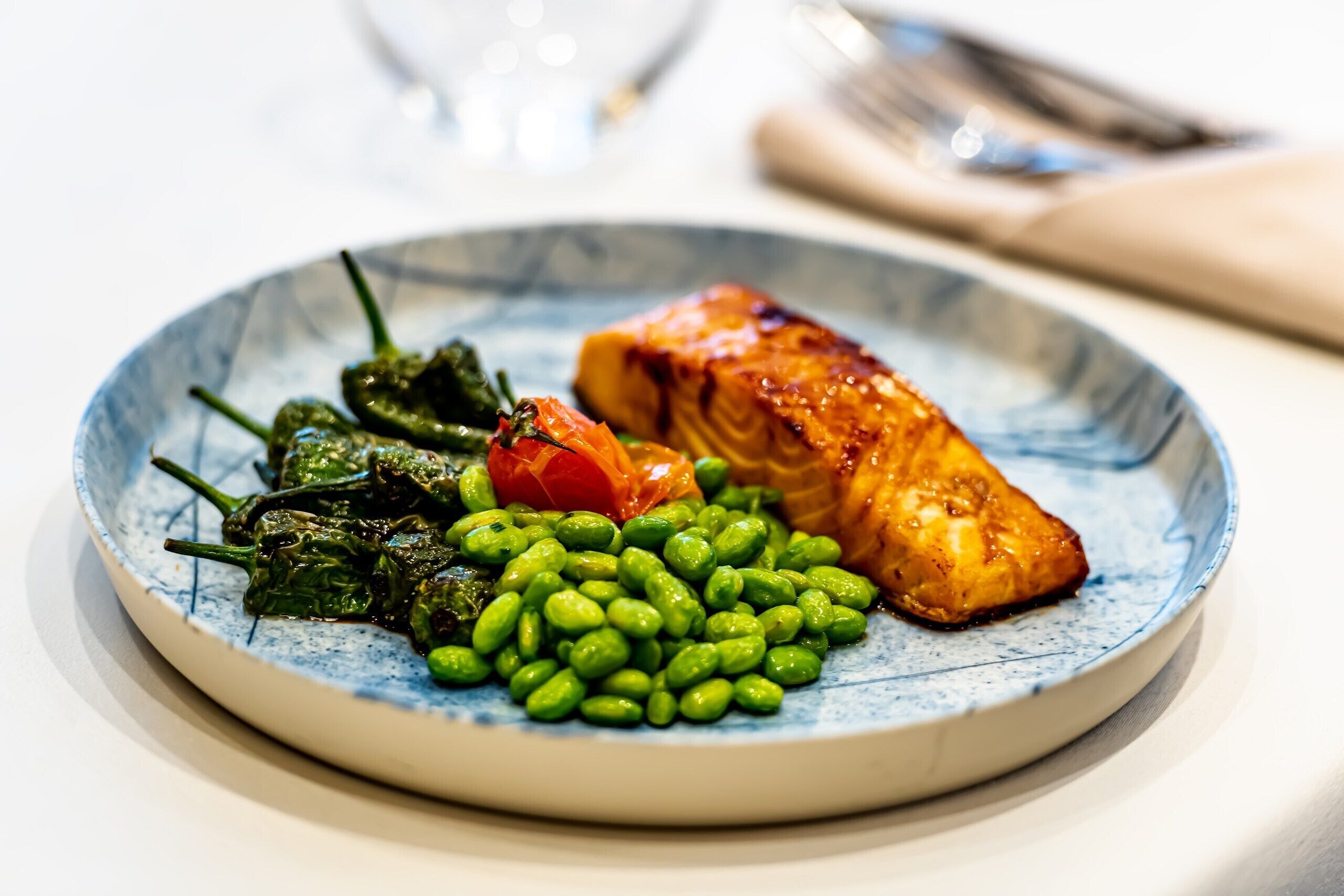 Un plato de comida, con judías verdes, espinacas y un trozo de salmón.