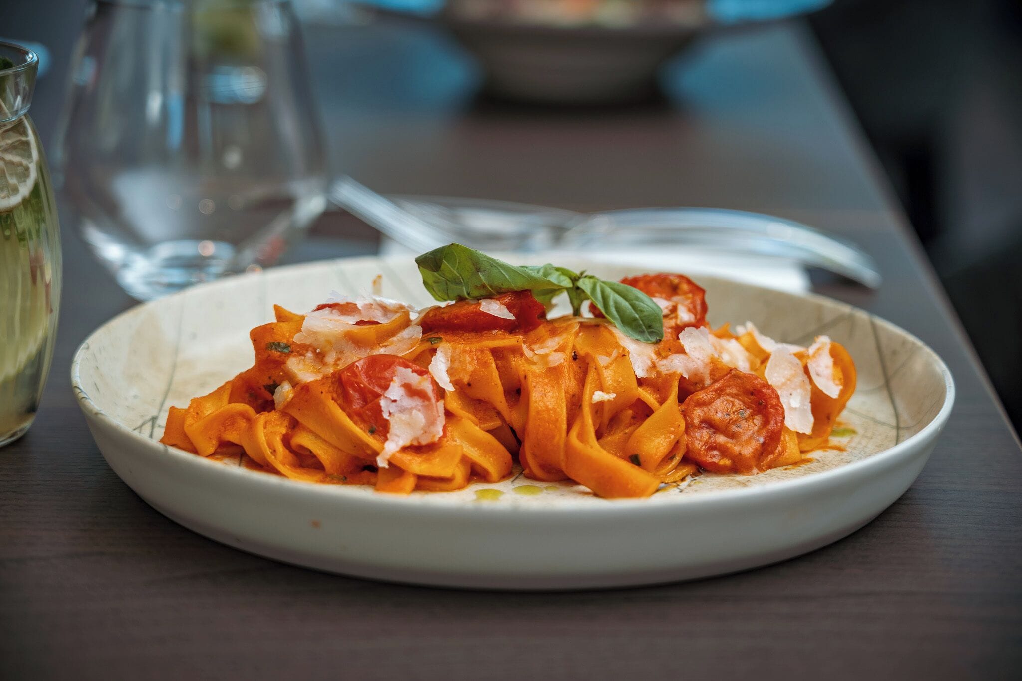 Un plato de pasta con salsa de tomate y albahaca sobre una mesa.