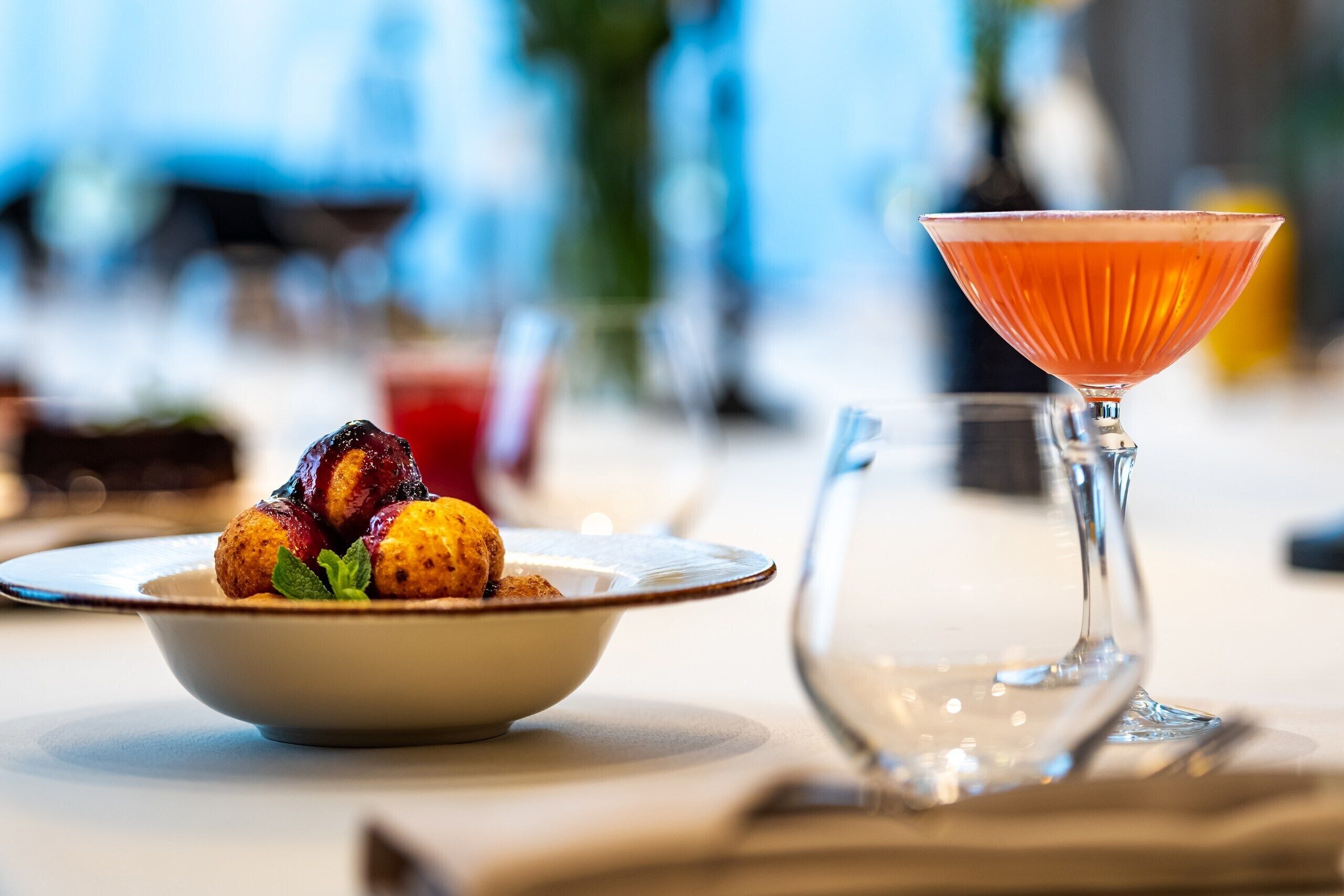Una mesa de comedor con un tazón de papas asadas y una copa de martini.