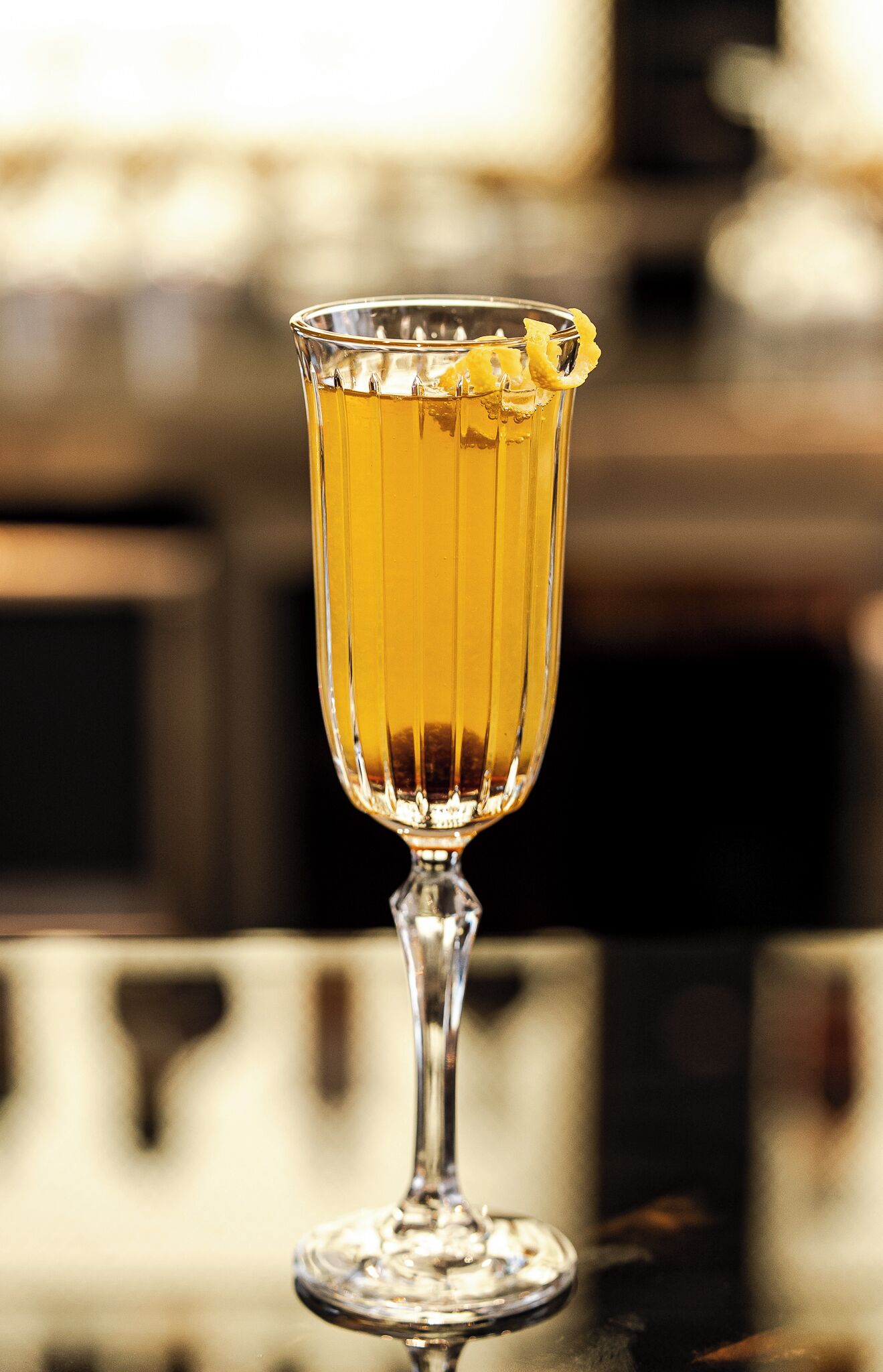 A clear glass with a lemon slice garnish on a reflective surface.