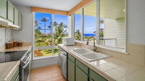 A kitchen with a large window, a dishwasher, and a microwave. - Princeville condo with ocean views, pool and hot tub access summer deals (PRINCEVILLE)