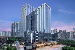 A modern high-rise building with a glass facade, surrounded by other high-rise buildings. - Home2 Suites BY Hilton Wuhan Xudong (Wuhan)