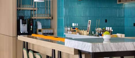 A modern kitchen with a central island, bar stools, and yellow pendant lights.
