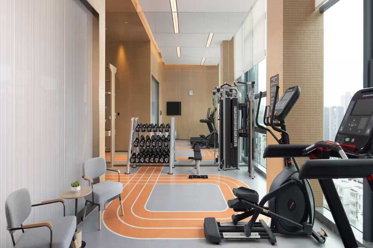 Ein Fitnessraum mit Trainingsgeräten, einem Gewichtständer und einer Tartanbahn.