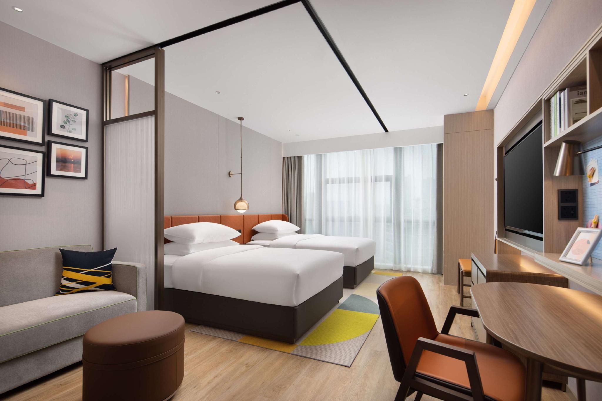 A hotel room with a bed, a sofa, a desk, and a TV.