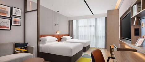 A hotel room with a bed, a sofa, a desk, and a TV.