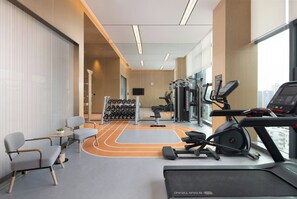 A modern gym with treadmills, weight machines, and a wall-mounted TV. - Home2 Suites BY Hilton Wuhan Xudong (Wuhan)