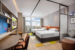 Una habitación de hotel moderna con un ventanal grande, dos camas, un escritorio y una zona de estar.