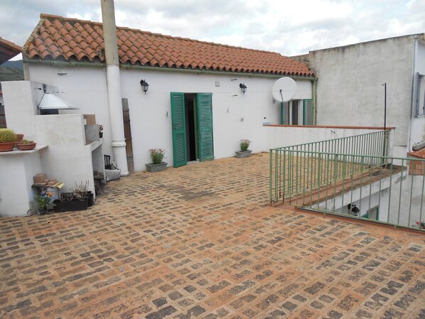 A courtyard with a tiled floor, a white building with green shutters, and a metal railing. - Detached house with courtyard and terrace, near the sea. Ideal for families. (San Vito)