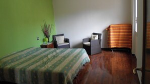 Ein Schlafzimmer mit einem Bett, zwei Stühlen, einer grünen Wand und Holzboden.