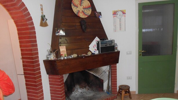 Ein gemütliches Wohnzimmer mit Kamin aus Backstein, einem hölzernen Sims und einer grünen Tür.