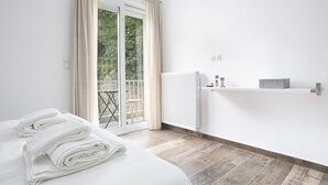 Een hotelkamer met een bed, een radiator, een plank met toiletartikelen en uitzicht op een balkon.