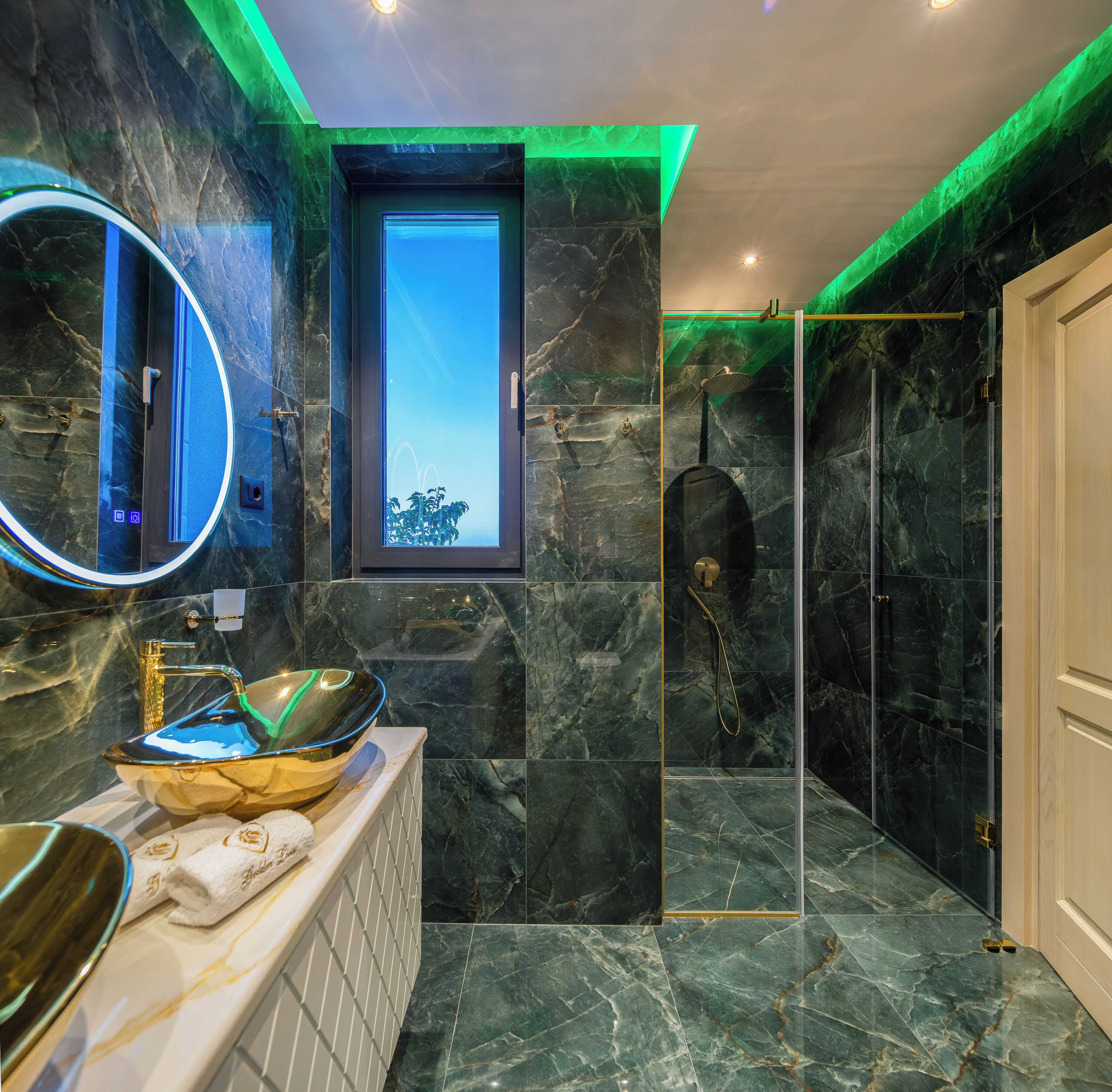 Un baño con ducha de vidrio, un espejo grande y piso de mármol.