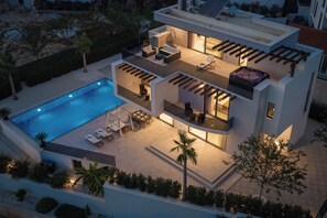 Een modern huis met twee verdiepingen, een zwembad, terras en een jacuzzi.