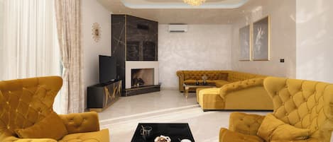 A modern living room with a fireplace, a sofa set, and two armchairs.