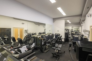 A gym with various exercise machines, a mirror, and a door.