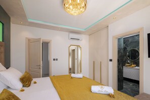 Een hotelkamer met een bed, een spiegel, een airconditioner en een badkamer met een marmeren wastafel.