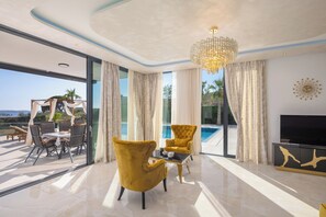 A modern living room with a large window, a pool view, and a yellow armchair.