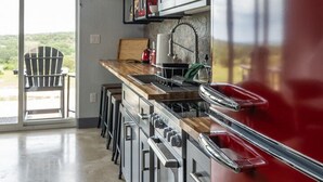A modern kitchen with a red Galanz refrigerator, stainless steel appliances, and a wooden countertop. - Willie In the Hill Country - Hacienda Amor (Johnson City)