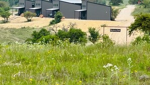 Un bâtiment moderne comprenant plusieurs logements, un chemin de terre menant à l’entrée, et une enseigne indiquant « Hacienda Amore ».