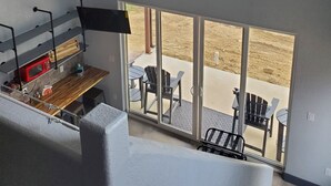 A spacious room with a ceiling fan, a guitar wall art, and a view of the outdoors through large windows. - Stevie Ray In The Hill Country - Hacienda Amor (Johnson City)