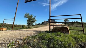 Una entrada rural con un letrero que dice "Hacienda Amor" y puertas de metal.