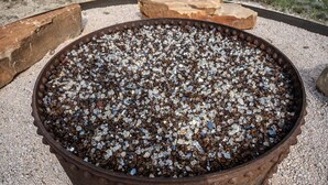 Un contenedor metálico grande y oxidado lleno de piedras pequeñas y multicolores.