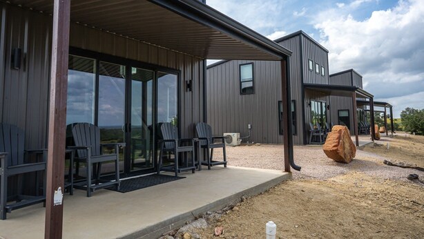 A modern building with a covered patio area, large windows, and outdoor seating. - Stevie Ray In The Hill Country - Hacienda Amor (Johnson City)