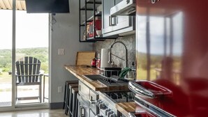 A modern kitchen with a red Galanz refrigerator, a wooden countertop, and a black chair. - Stevie Ray In The Hill Country - Hacienda Amor (Johnson City)
