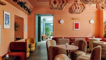 Un restaurant avec des chaises rouges et beiges, des tables rondes et des lampes suspendues.