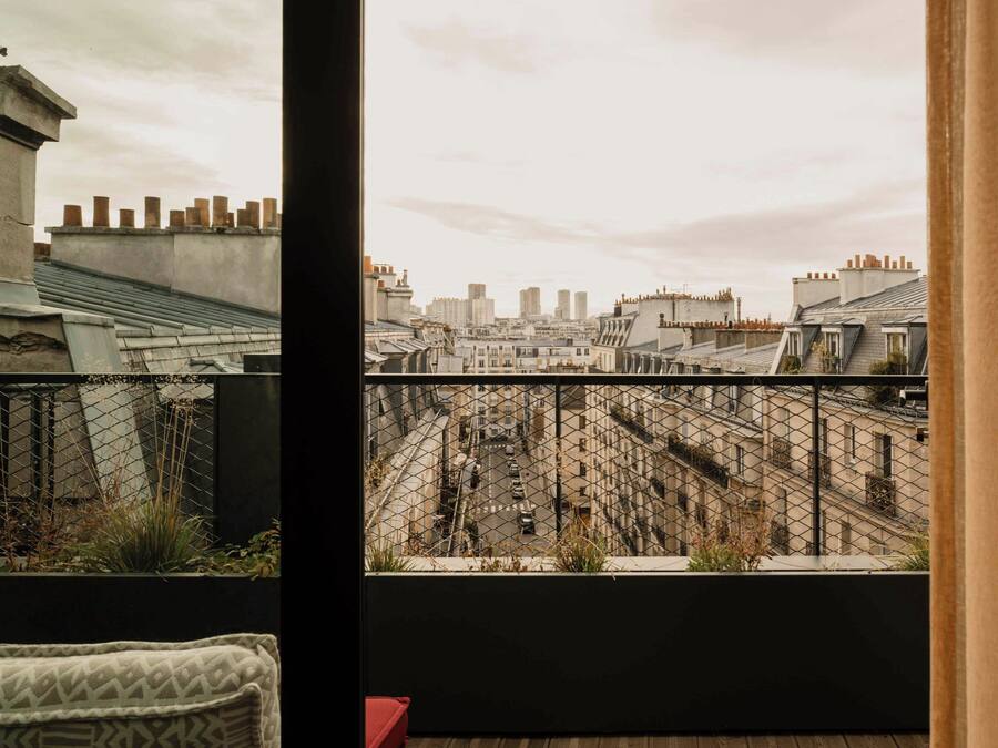 A view from a balcony with a cityscape, including buildings and a fence.