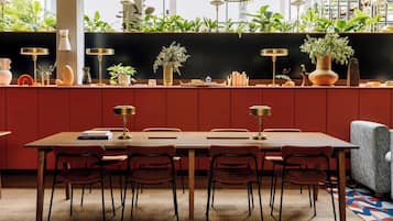 Un comedor con una mesa de madera larga, seis sillas y diversos objetos decorativos, como jarrones y libros.