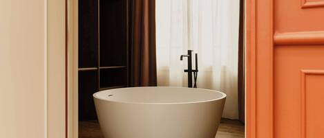 A modern bathroom with a freestanding bathtub, a towel rack, and a wooden floor.