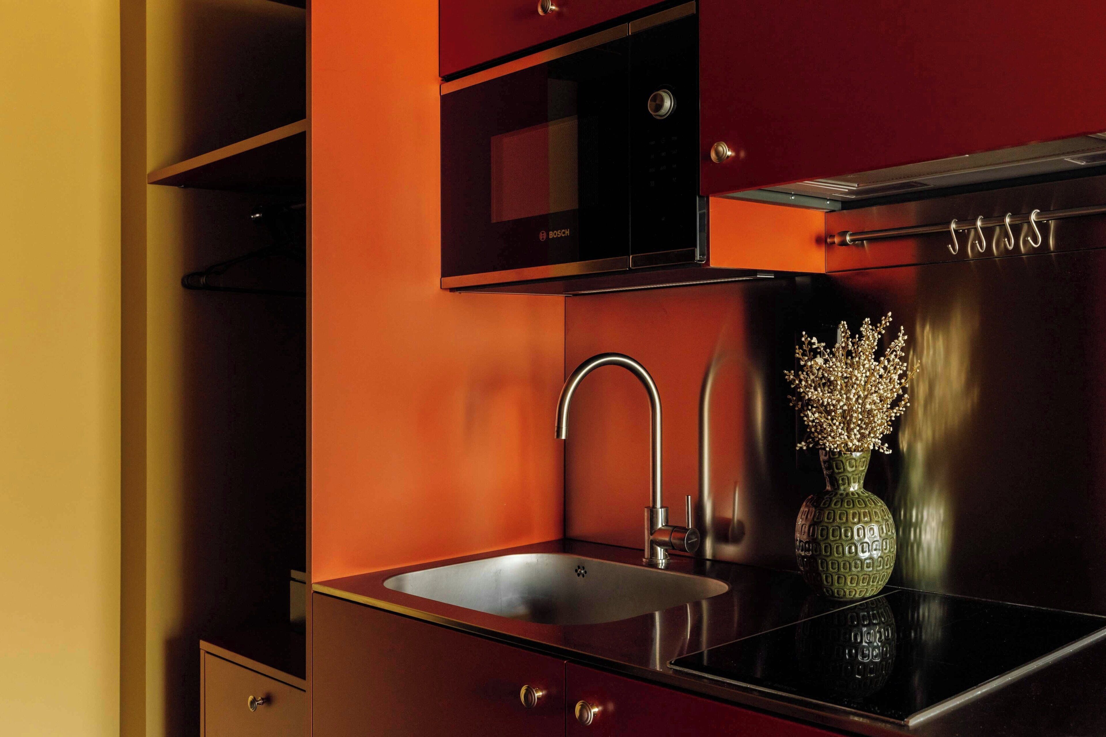 A kitchen with a Bosch microwave, stainless steel sink, and a vase with flowers.