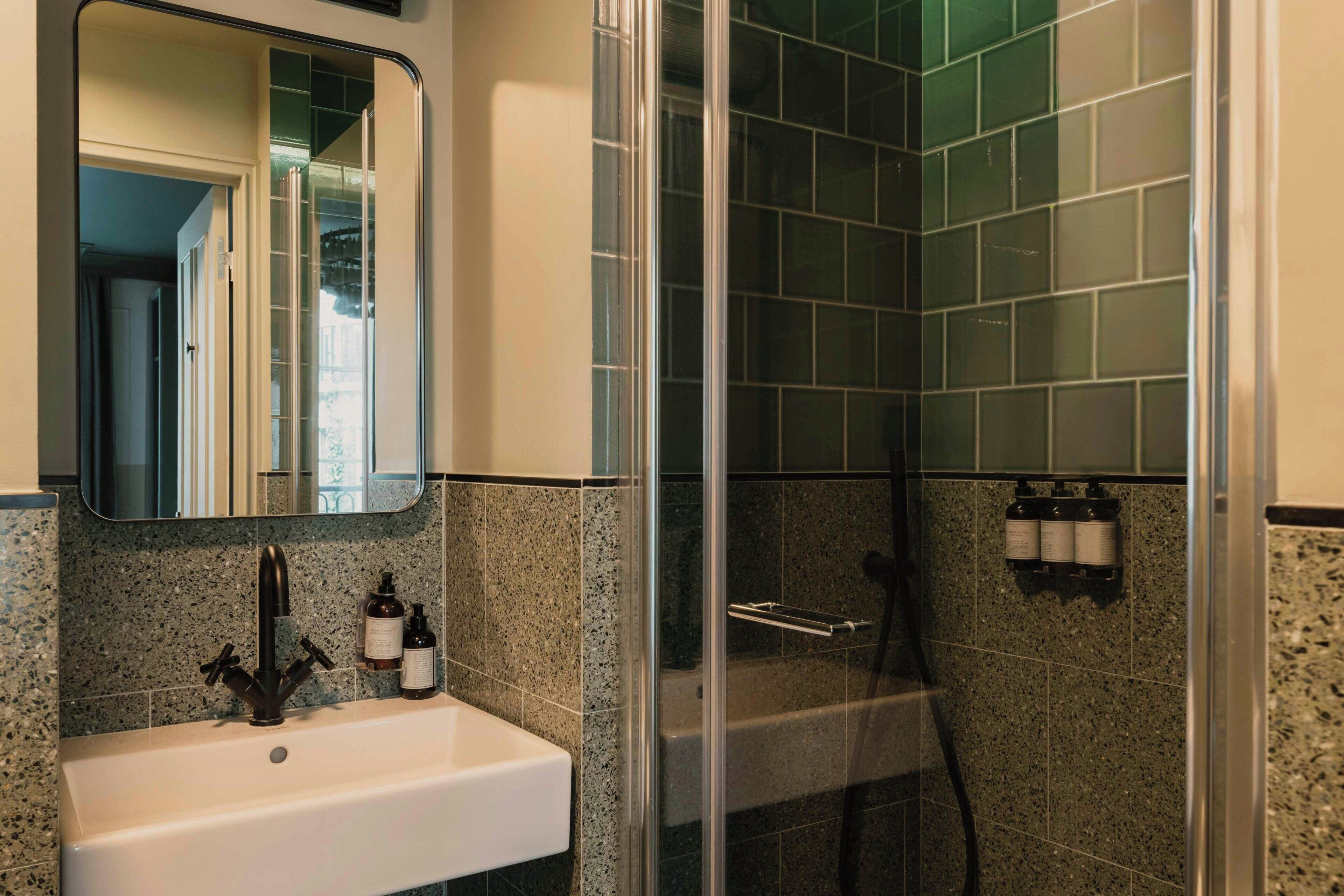 A bathroom with a sink, mirror, and shower.