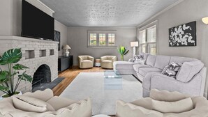 A living room with a fireplace, two armchairs, a sofa, and a flat-screen TV.