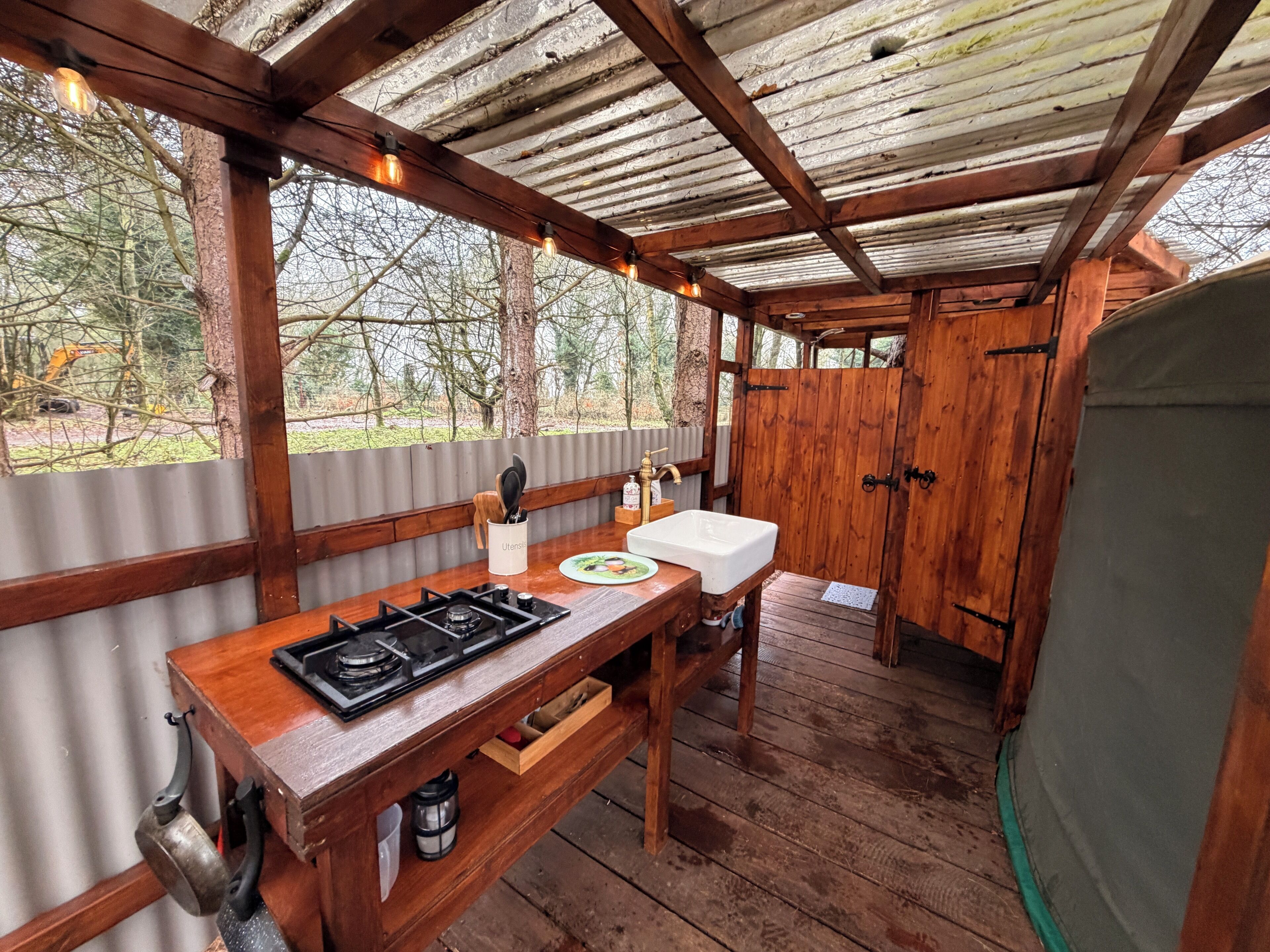 A rustic wooden cabin with a kitchenette, including a stove, sink, and wooden cabinets.