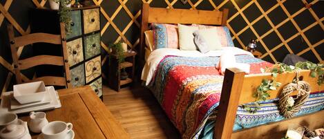Una tienda acogedora y bien iluminada con una cama de madera, una mesa con juego de té y un aparador decorativo.