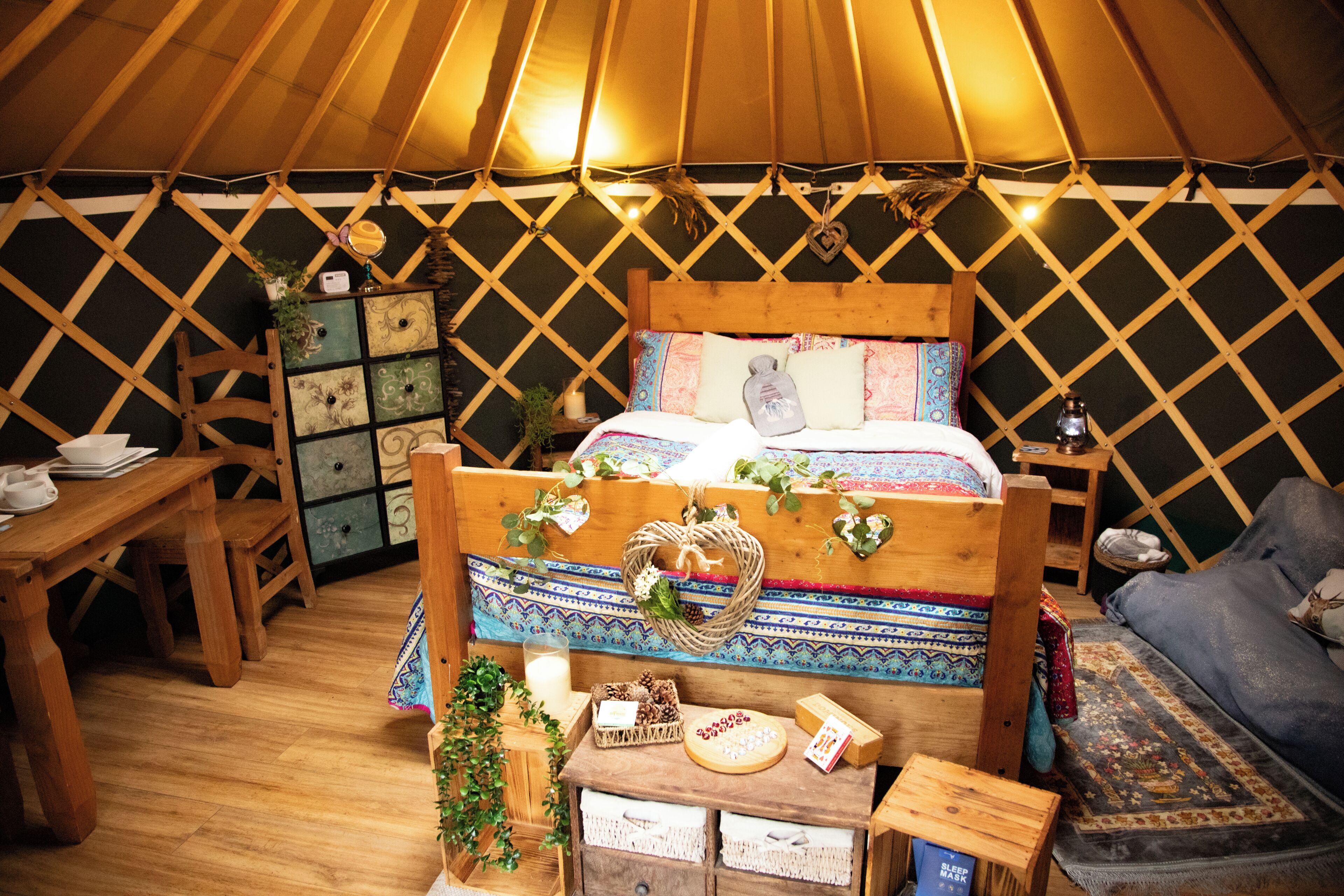 Interieur van een joert met een houten bed, een tafeltje en een bank.
